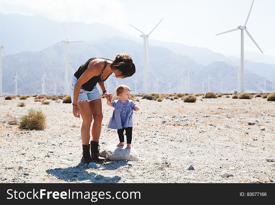 Woman Holding Her Child Walking Near Windmills