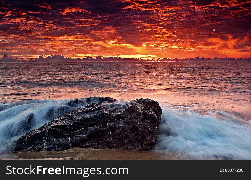 A sunset on the beach with waves hitting the rocks. A sunset on the beach with waves hitting the rocks.