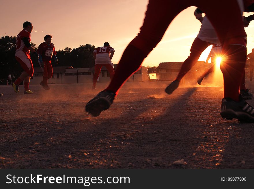 A group of men training for American football at sunset. A group of men training for American football at sunset.
