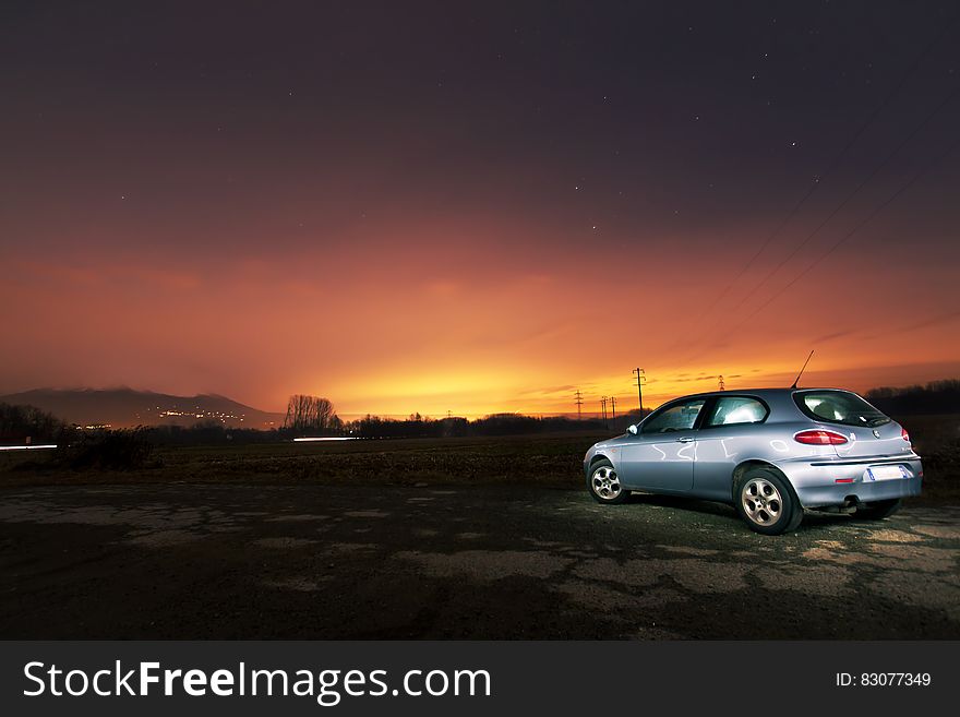 A car parked on field at sunset. A car parked on field at sunset.