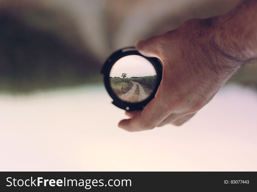 A man holding a lens showing the world in focus with defocused background. A man holding a lens showing the world in focus with defocused background.
