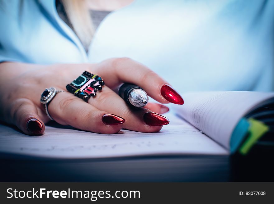 Person With Red Nail Polish Holding Black Pen