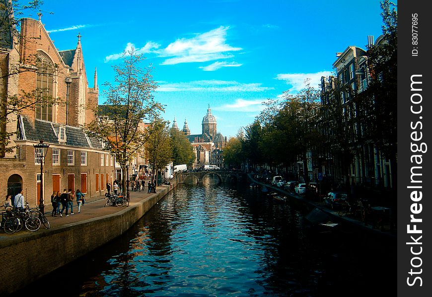 A canal in Amsterdam, people and buildings on its banks.