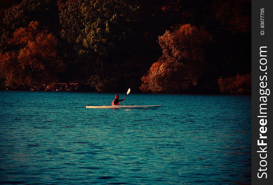 A kayak on a lake with a person in it. A kayak on a lake with a person in it.