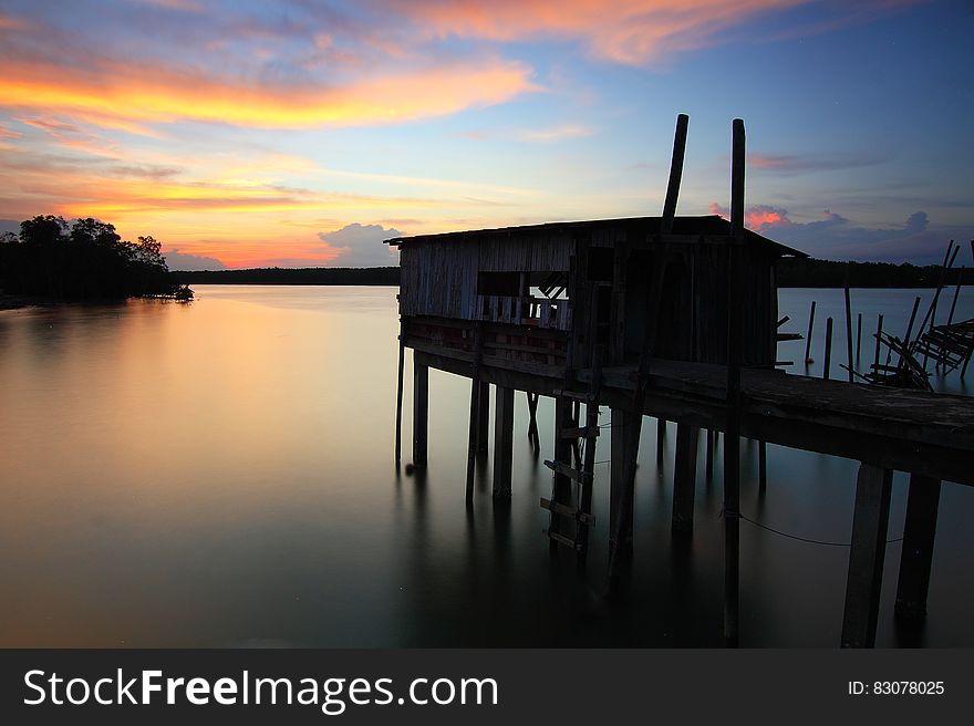 Silhouette of House on Top of Ocean Water during Sunset