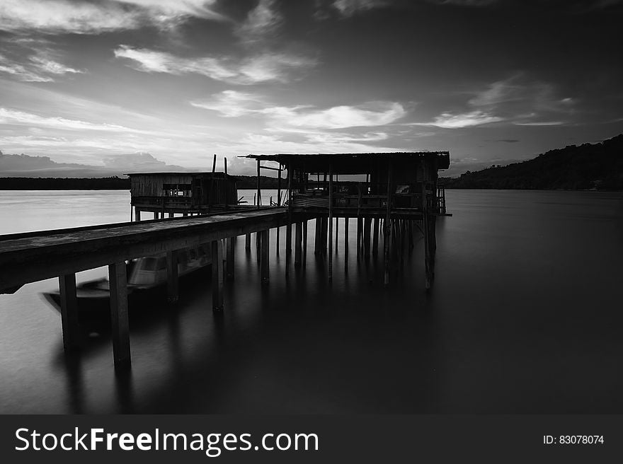 Greyscale Photo Of Dock Near Mountains