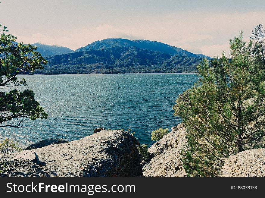 A view over a blue lake from rocks at the shore and hills on the distance. A view over a blue lake from rocks at the shore and hills on the distance.