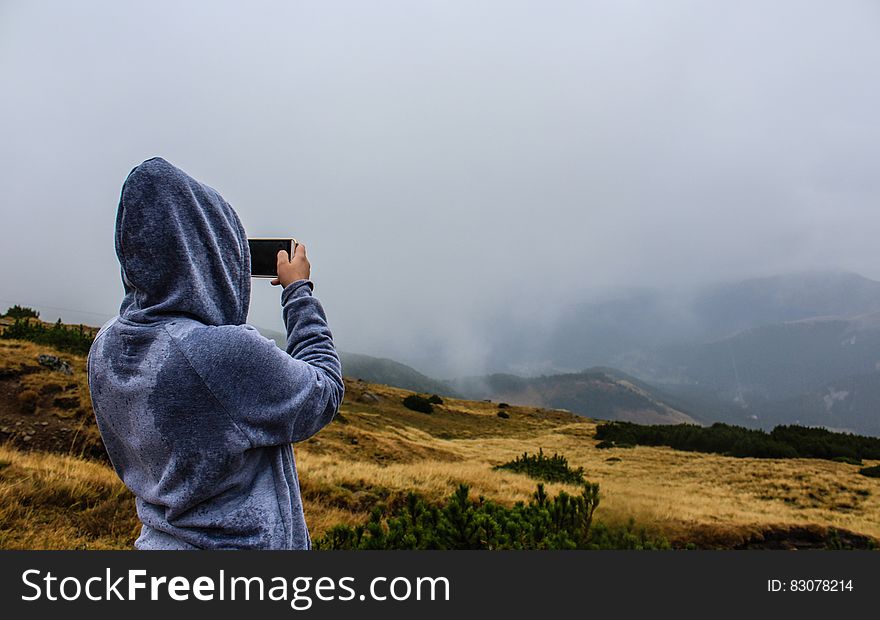A person with a wet sweater taking a photo of a rainy landscape. A person with a wet sweater taking a photo of a rainy landscape.