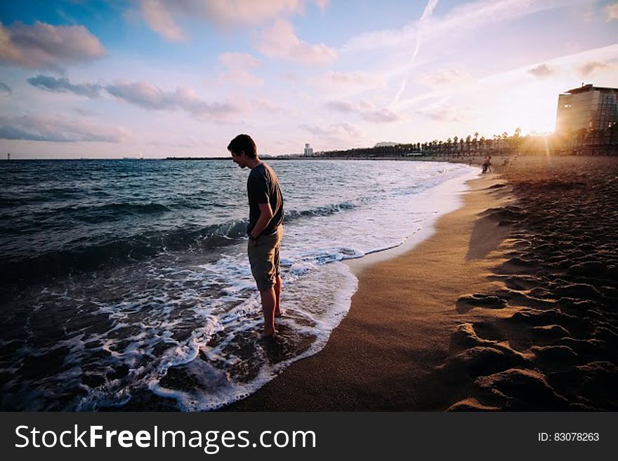 A man standing at the seashore watching the sea. A man standing at the seashore watching the sea.