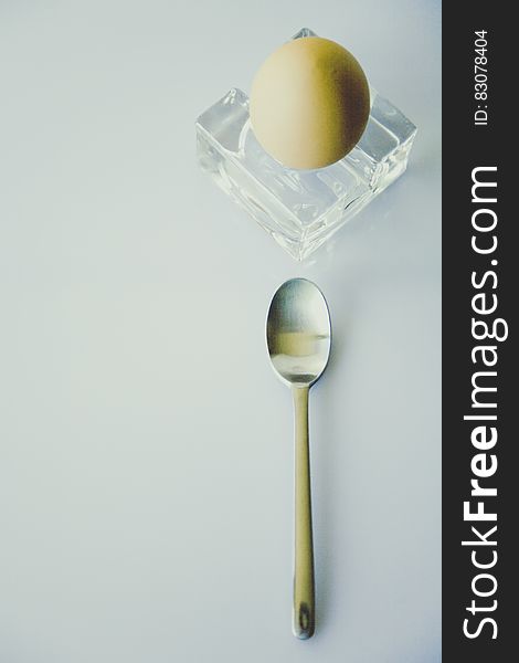 Stainless Steel Spoon Beside Yellow Egg on Clear Glass Fragment