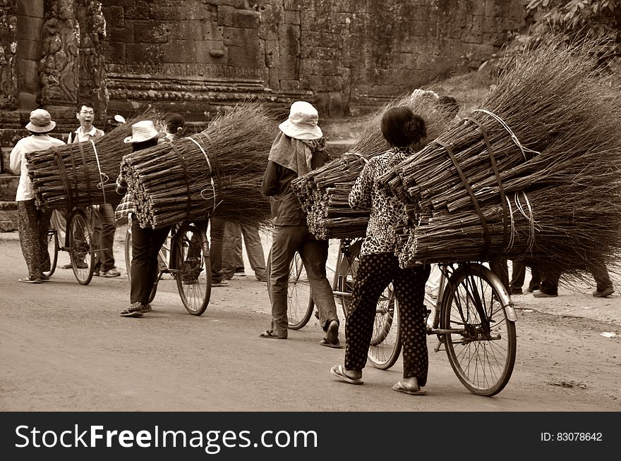 Asian workers transporting brooms on bicycles on the road