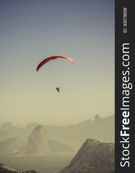 Person in Parachute Gliding Above Mountains