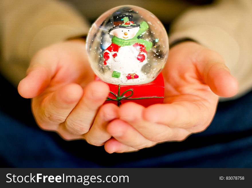 A snowglobe with a snowman being held in someone &#x27;s hands. A snowglobe with a snowman being held in someone &#x27;s hands.