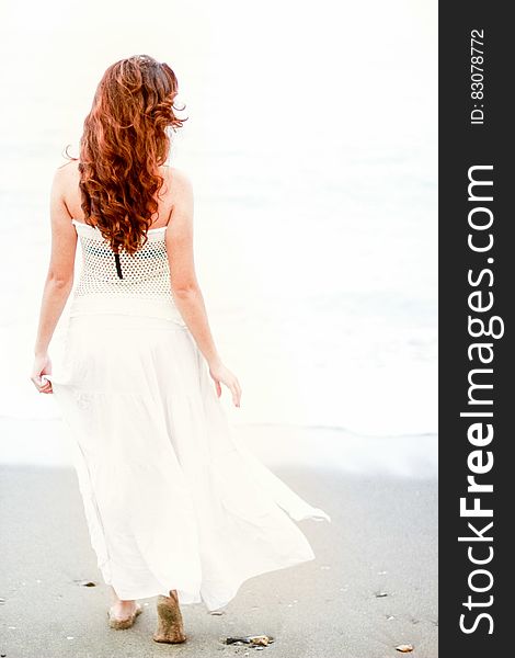 Redhead woman walking on the beach on a sunny summer day. Redhead woman walking on the beach on a sunny summer day.