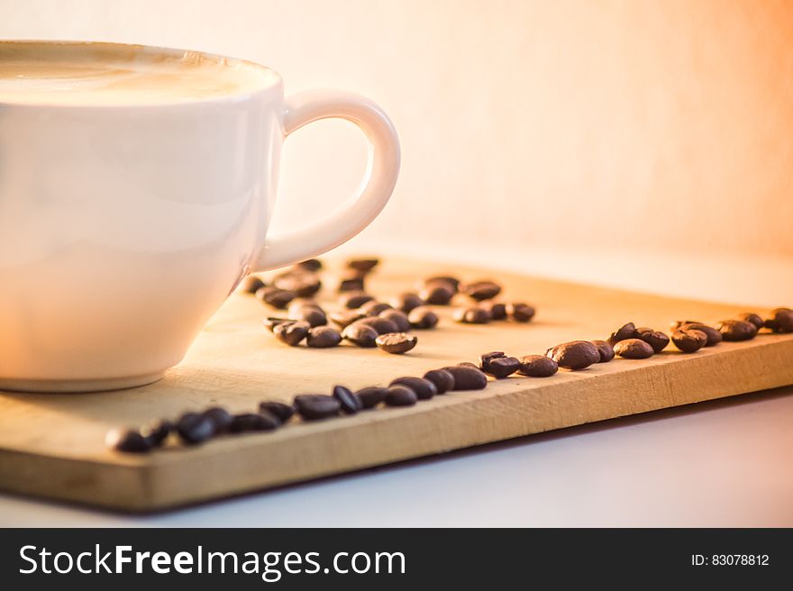 White Ceramic Coffee Mug With Cream Beside Black Coffee Beans