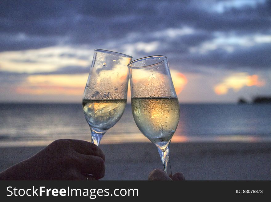 Couple celebrating with glasses of champagne at the beach during sunset. Couple celebrating with glasses of champagne at the beach during sunset