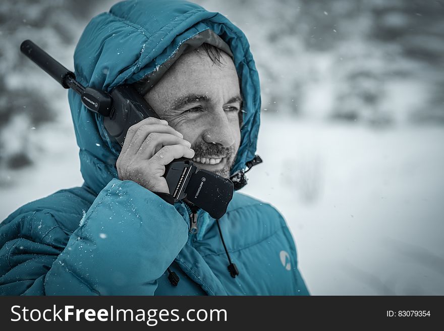 Man in Blue Hoodie Jacket Holding Black Radio Receiver during Snowy Day Time
