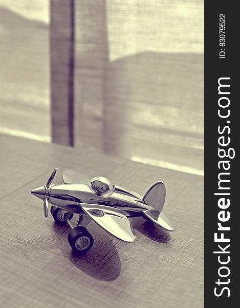 Sepia Photography of Stainless Steel Biplane on Brown Wooden Table Near Window during Daytime