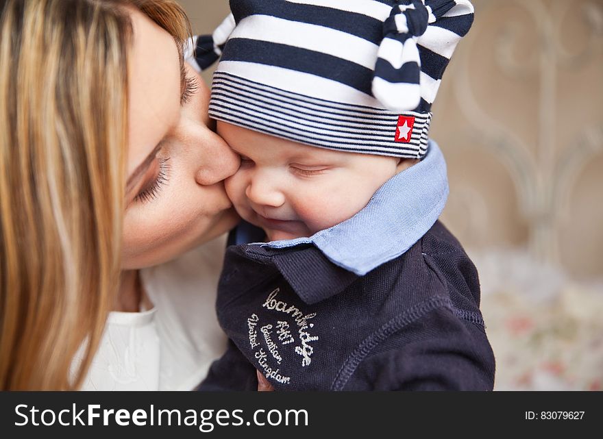 Woman in White Shirt Kissing Baby With Black and White Stripe Knit Cap