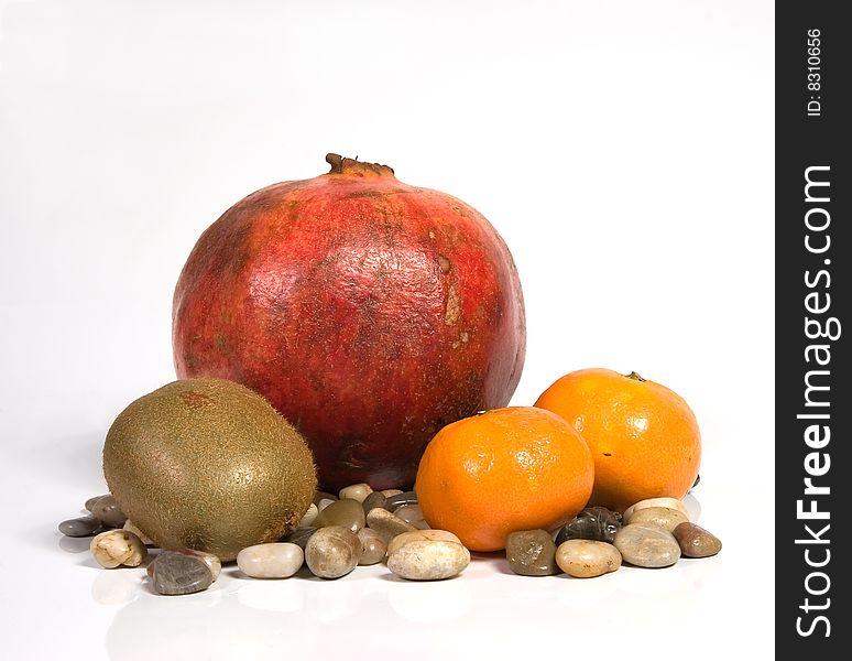 Pomegranate, tangerines, kiwi and sea stones on a white background. Pomegranate, tangerines, kiwi and sea stones on a white background