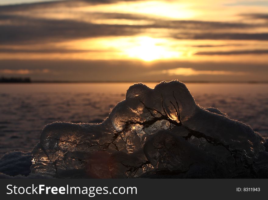 Sunset over frozen lake in winter, Finland, frozen branch detail