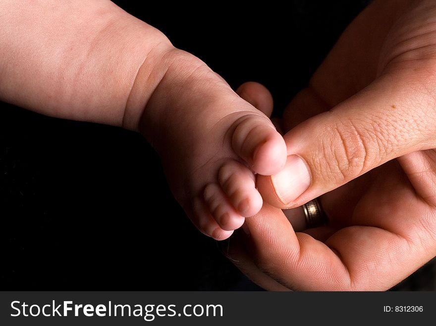 Baby's foot with dads big hand tickling it softly. Baby's foot with dads big hand tickling it softly.