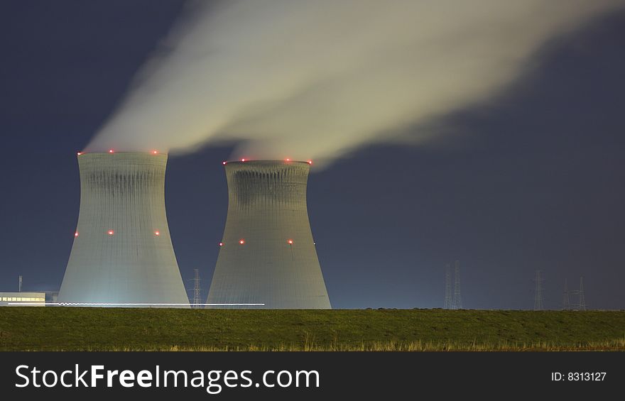 A nuclear plant by night, with a lightning stripe in the front from a vehicle