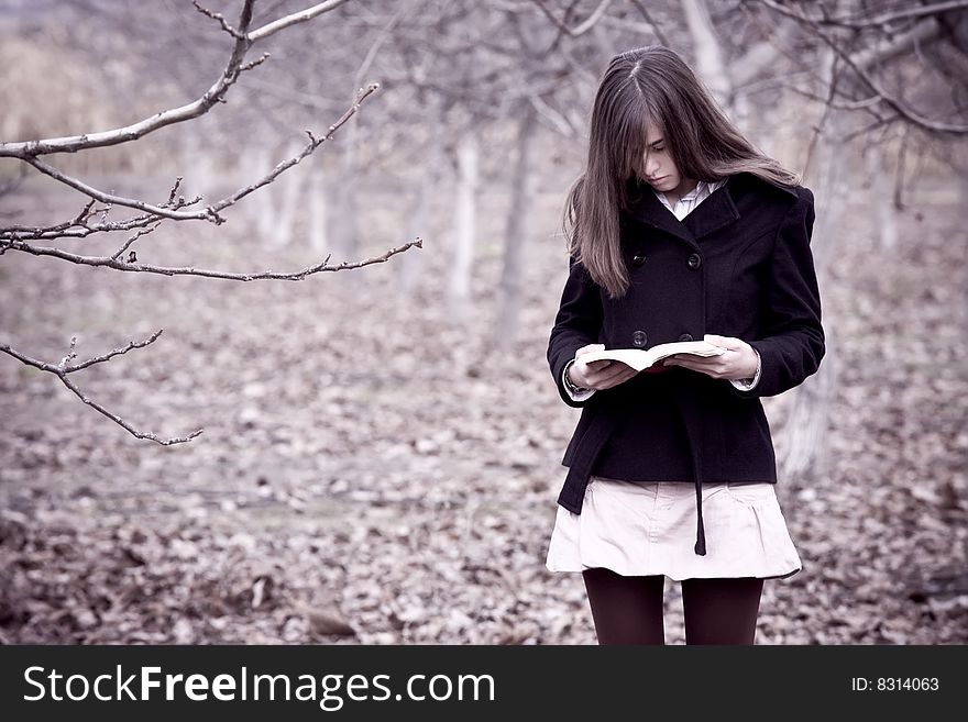 Young woman reading a book in the forest.