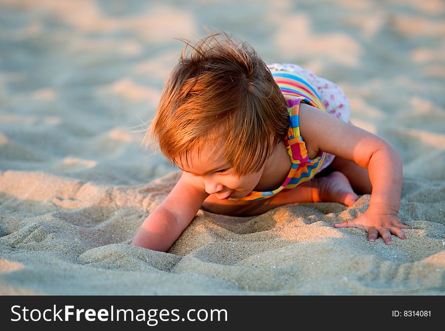 A baby-girl playing with sand on a beach. A baby-girl playing with sand on a beach