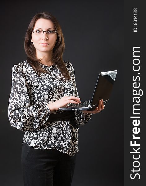 Business woman with a mobile computer against a dark background. Business woman with a mobile computer against a dark background