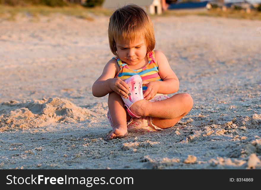 A baby-girl sitting on a beach down-under with one shoe missing. A baby-girl sitting on a beach down-under with one shoe missing