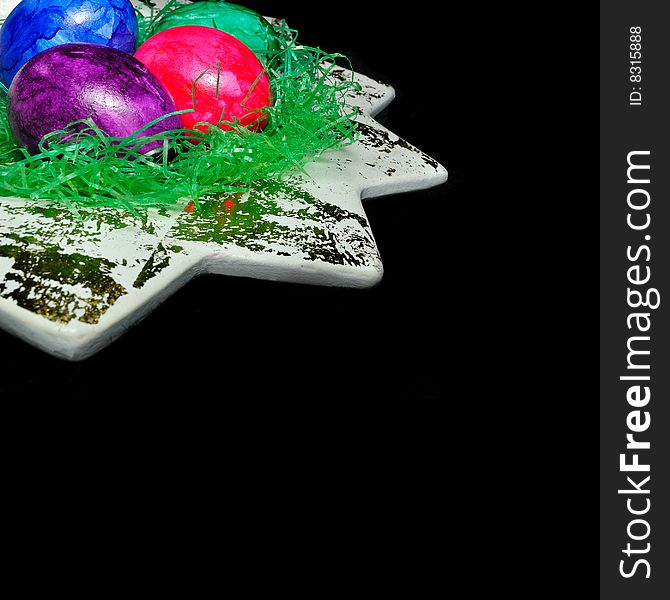 Colorful Easter eggs in a dish on the black background