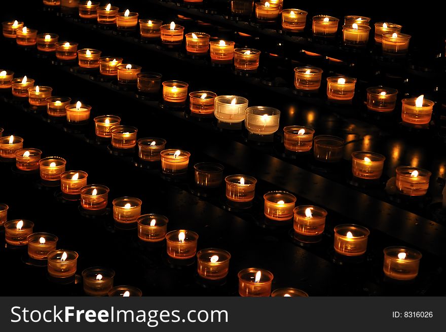 Candle lights arranged in rows, on the black background