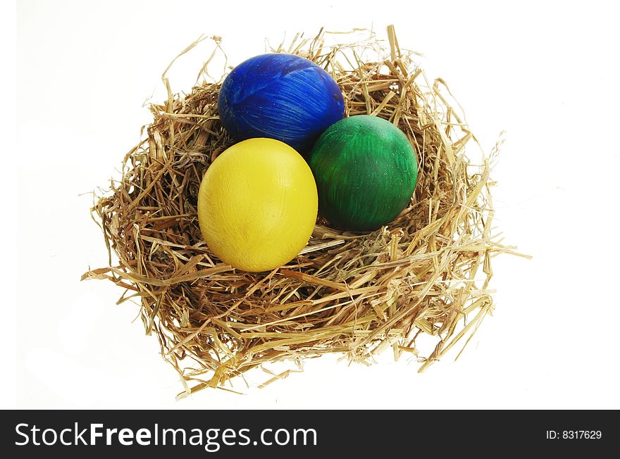 Painted eggs in a straw nest isolated on white
