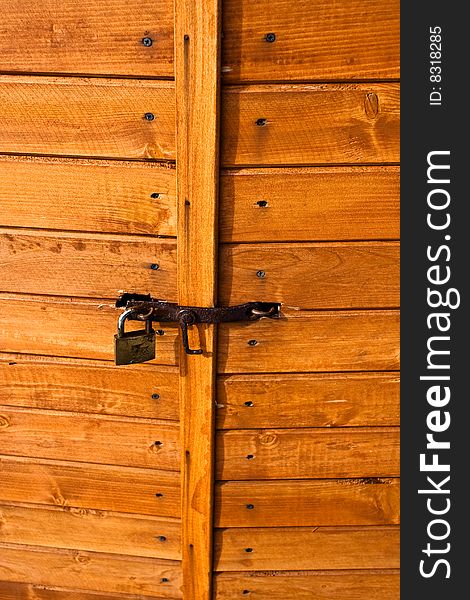 Closed wooden door and rusty padlock. Closed wooden door and rusty padlock.