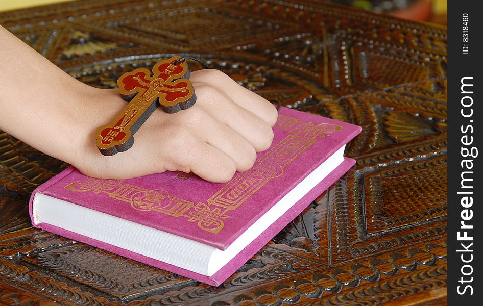 Hand on red Bible with wooden cross. Hand on red Bible with wooden cross