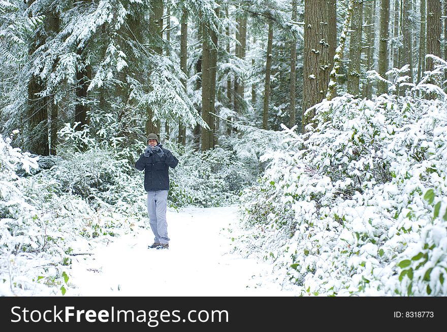 Young man stands in the snowy forest with camera. Young man stands in the snowy forest with camera