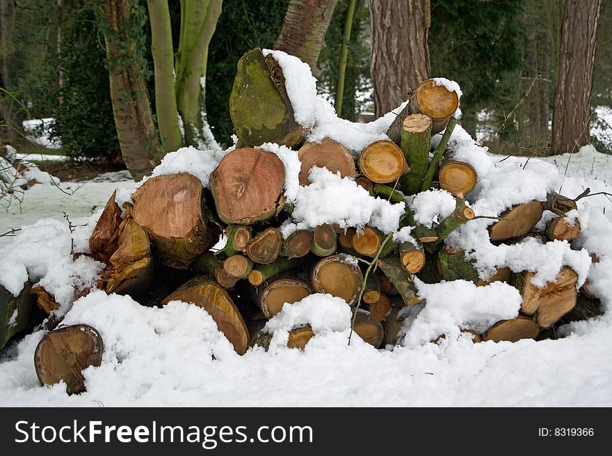 A pile of sawn logs covered in a blanket of fresh snow. A pile of sawn logs covered in a blanket of fresh snow