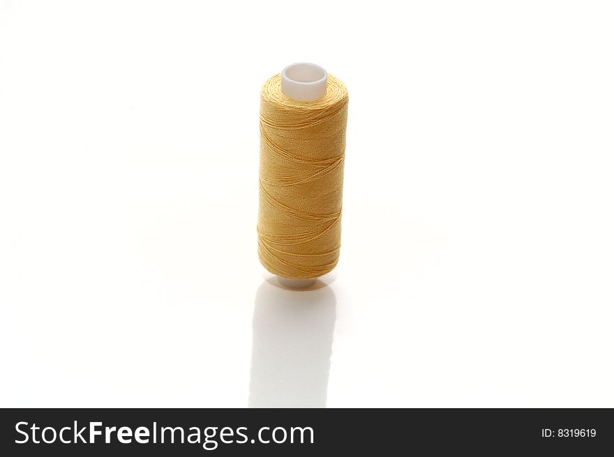 Yellow spool of sewing threads. Isolated