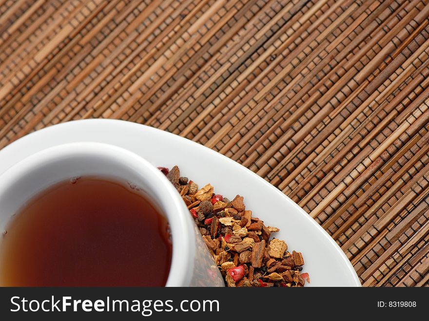 Closeup photo of a cup of spice tea on a wooden mat, with loose leaves and spices on the plate next to cup. Closeup photo of a cup of spice tea on a wooden mat, with loose leaves and spices on the plate next to cup.
