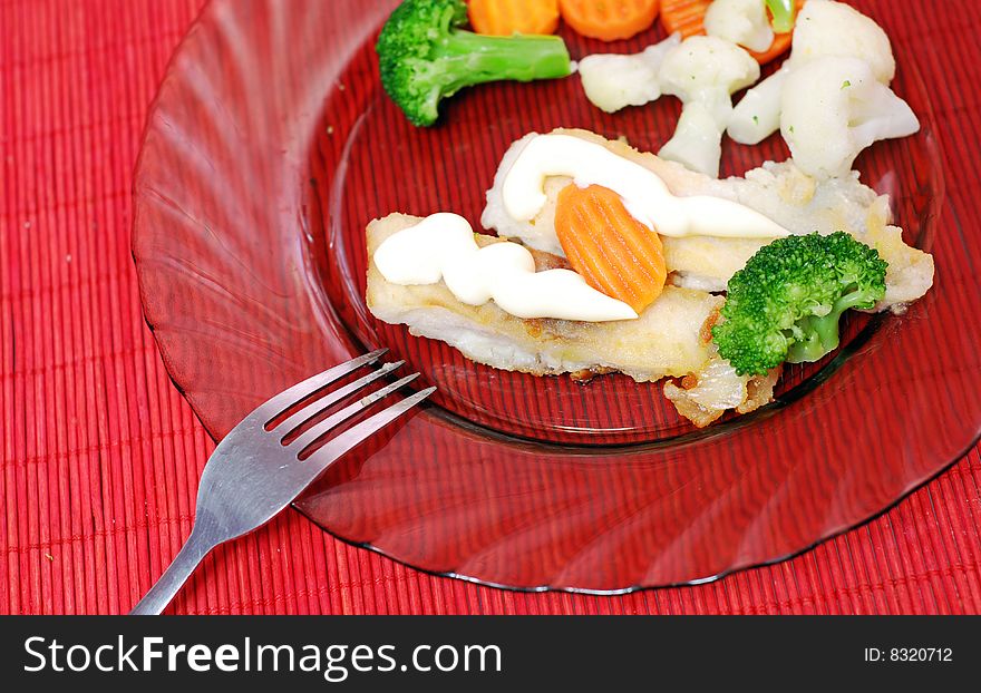 Plate with fish and vegetables on red table. Plate with fish and vegetables on red table