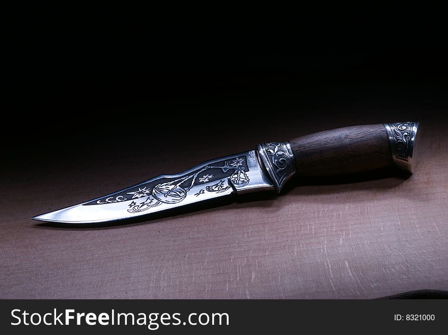 Ornate steel knife on a wood table