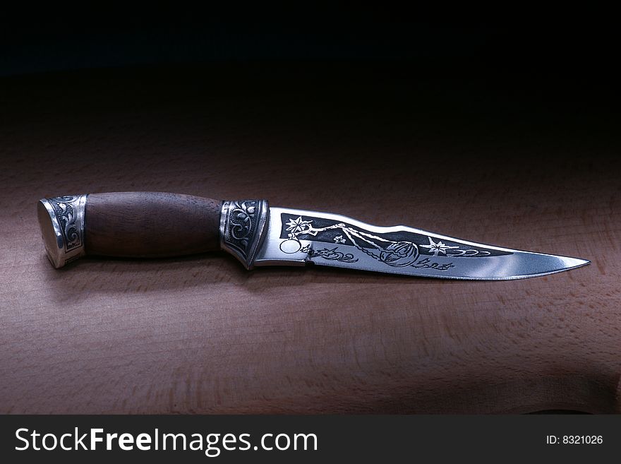 Ornated steel knife on a wood table