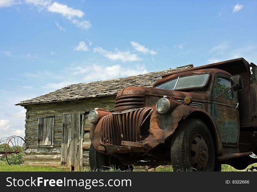 Old rusty truck sitting next to an old house on a clear day