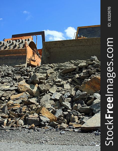 A pair of large machinery working on a empty lot moving rock around. A pair of large machinery working on a empty lot moving rock around