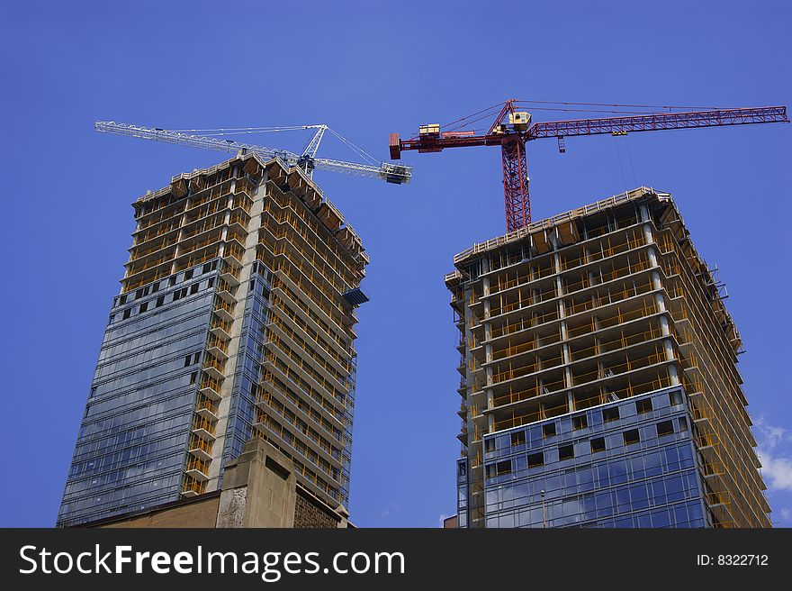 Two cranes atop twin highrise tower construction site. Two cranes atop twin highrise tower construction site