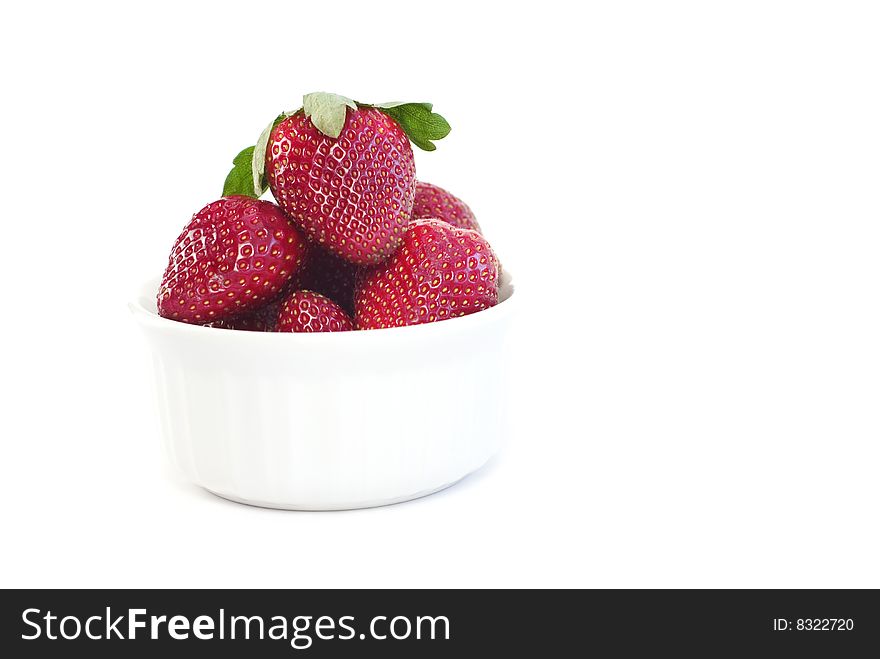 A small white bowl full of fresh whole strawberries isolated on white background with copy space. A small white bowl full of fresh whole strawberries isolated on white background with copy space