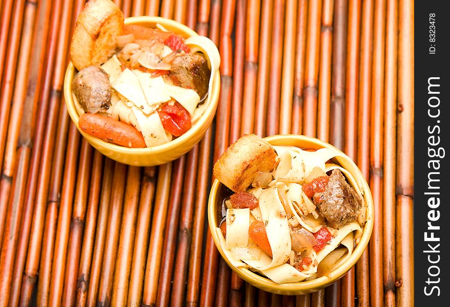 Beef noodle soup with large crouton on bamboo