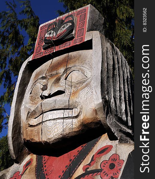 First Nation statue carved of wood with dark blue sky in the background. Located at Capilano Park North Vancouver BC. First Nation statue carved of wood with dark blue sky in the background. Located at Capilano Park North Vancouver BC