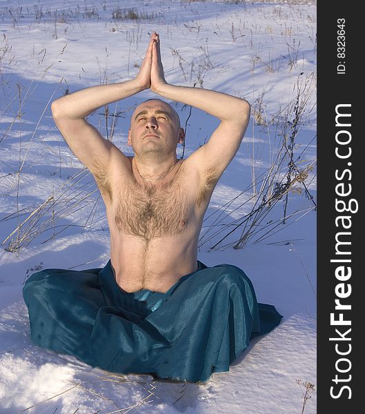 Man Doing Yoga Over Snow In Winter